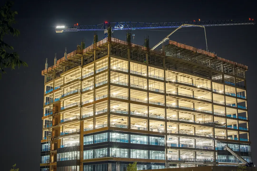 Building under construction with a tower crane at night