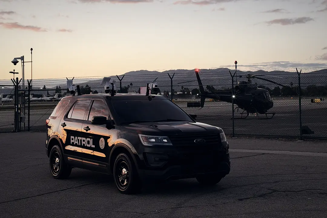 LDG camera-equipped Ford Explorer at an airfield at sunset with a helicopter behind it