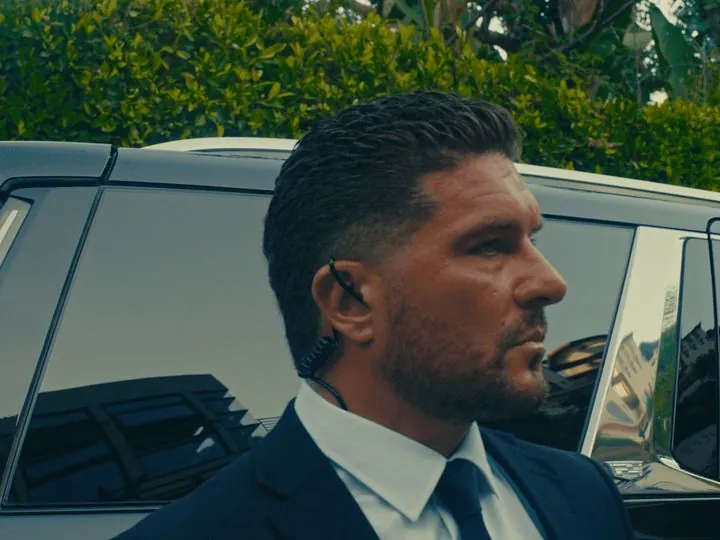 LDG protection agent in a suit standing by a black vehicle