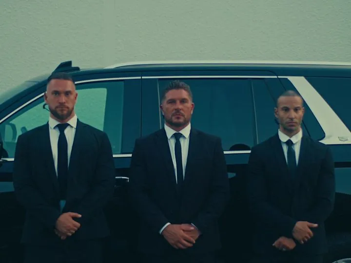 LDG officers in suits standing beside a black SUV