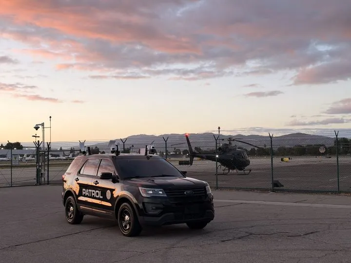 LDG patrol vehicle at an airfield at sunset with a helicopter behind it