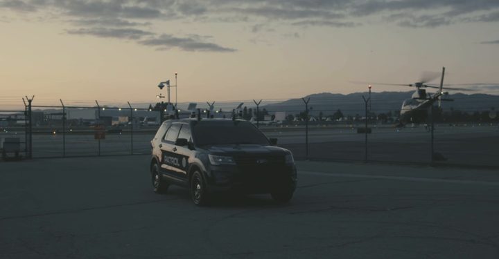 LDG surveillance vehicle on an airfield with a helicopter behind it